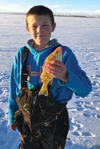 Trei holds up a fish caught while ice-fishing