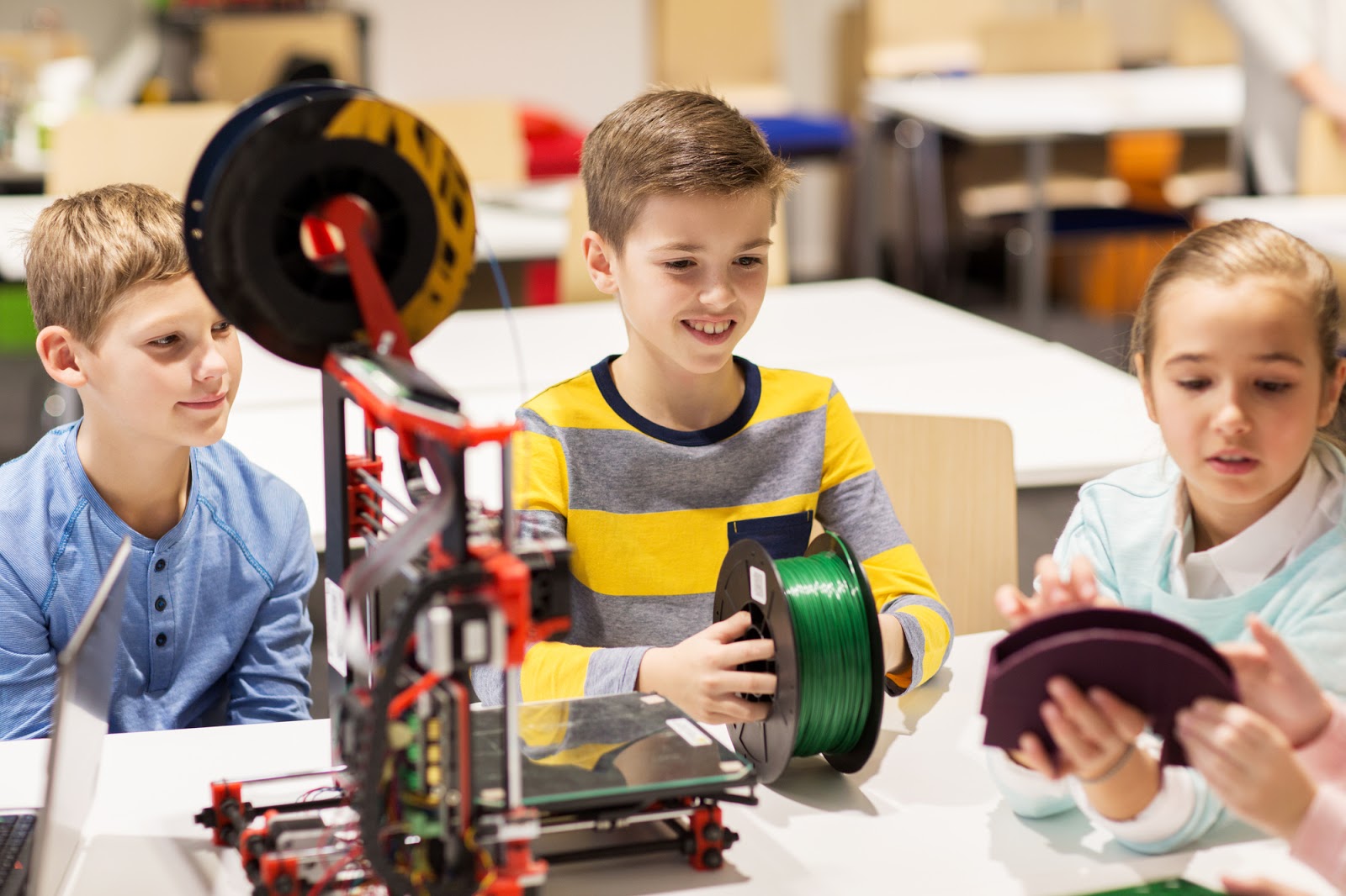 Three students working with a 3D printer