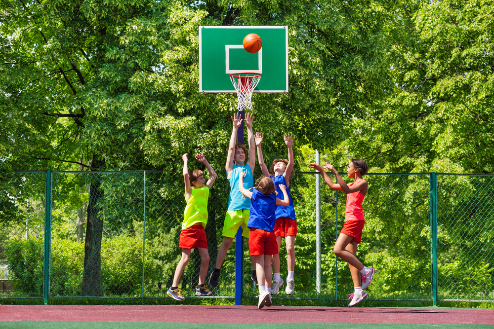 Happy teenagers playing basketball on playground