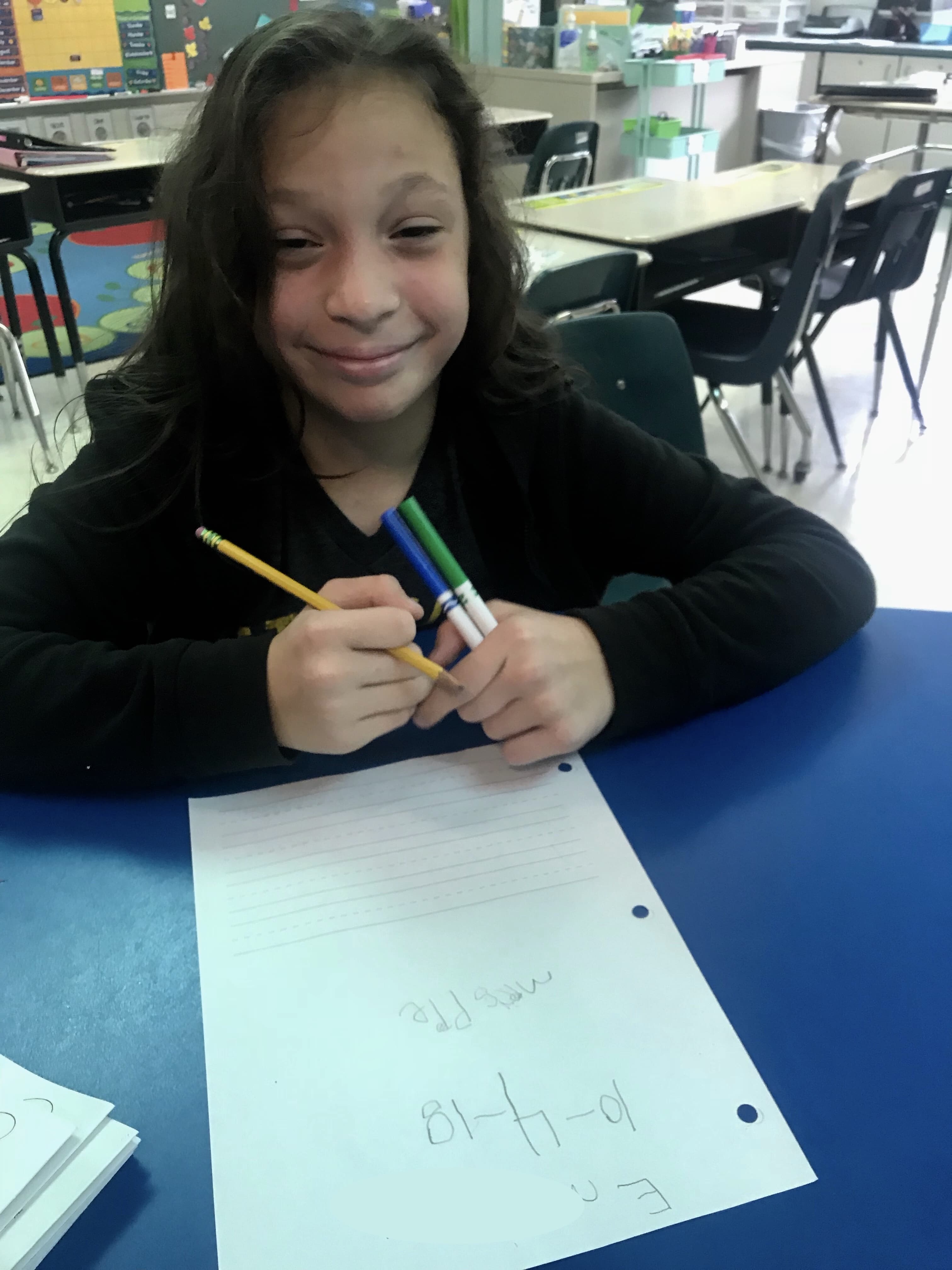 Student writing and smiling at the camera