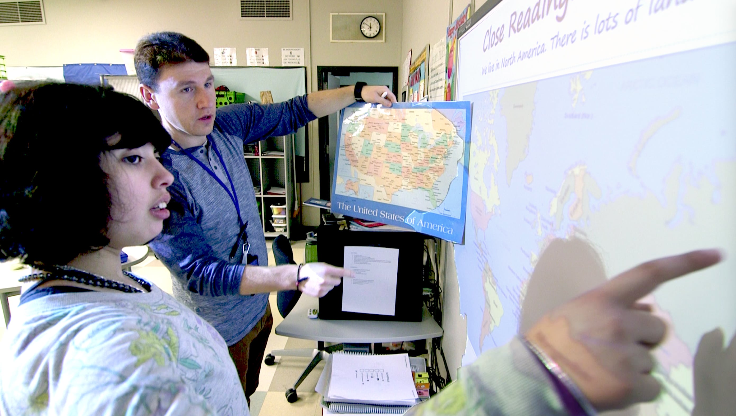 Erlind and a student comparing a map on the wall to a map in the lesson