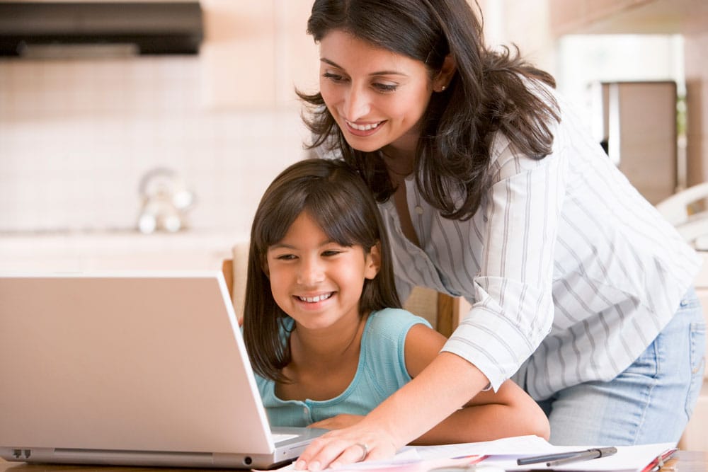 Parent helping child use laptop to learn at home
