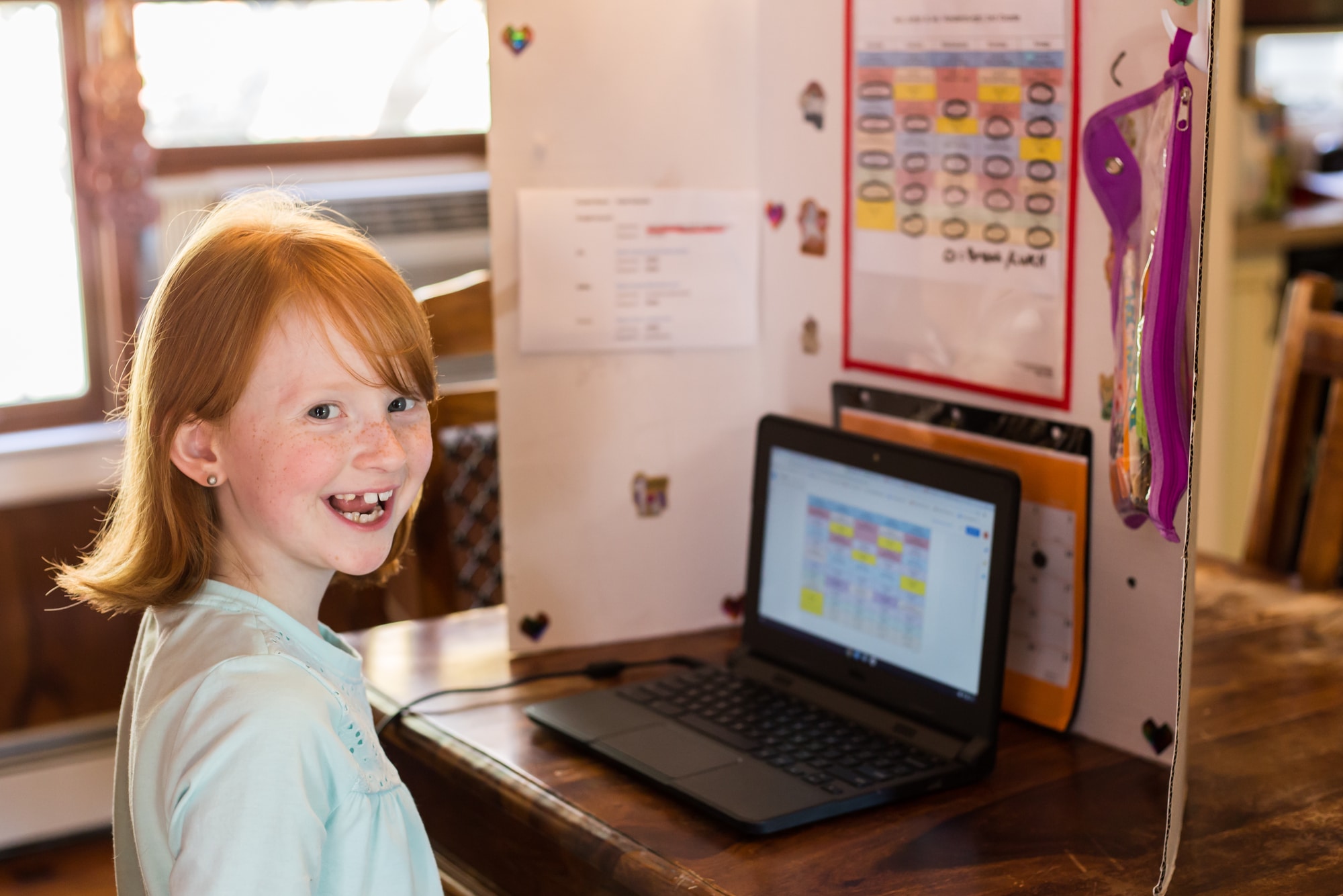 Student smiling at the camera in front of a chromebook