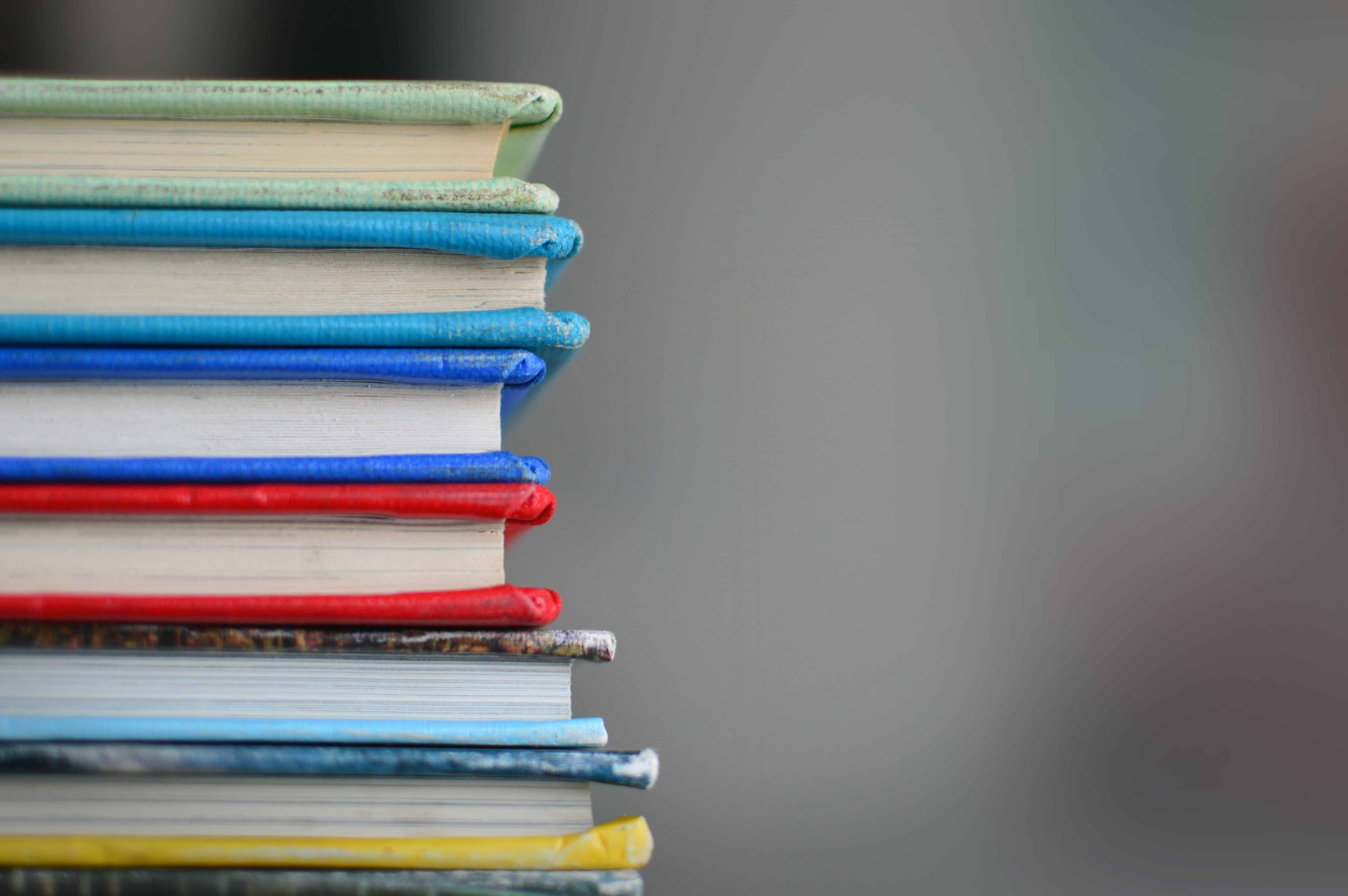 A stack of used books each bound in different colors.